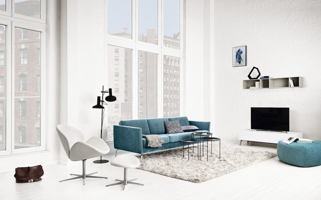 Blue 3-place sofa and a white armchair with a footstool by BoConcept